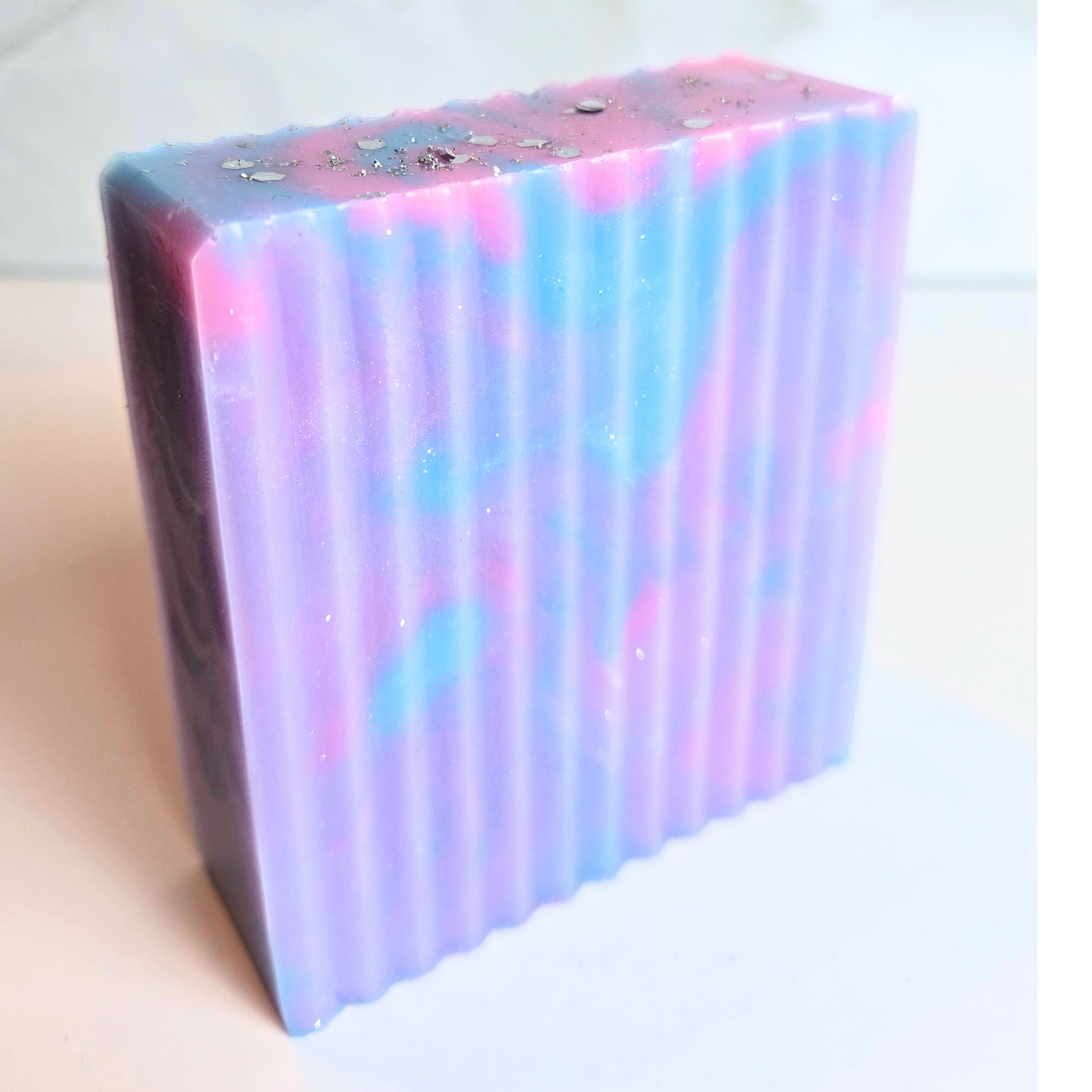 Colorful handmade soap bar with glitter and artistic design, side view.