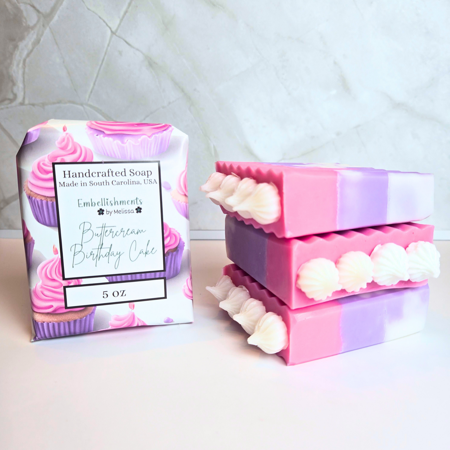 Handcrafted soap shaped like a pink and purple buttercream birthday cake slice, front view.
