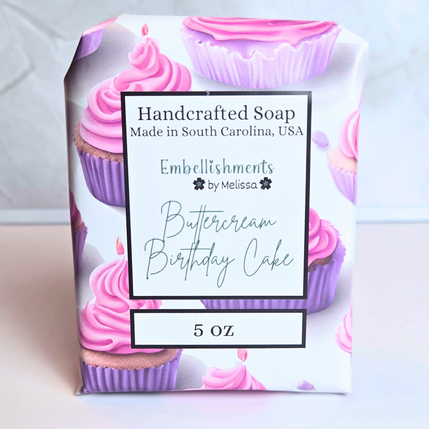 Cute handcrafted soap designed like a frosted birthday cake in pastel tones, front view.
