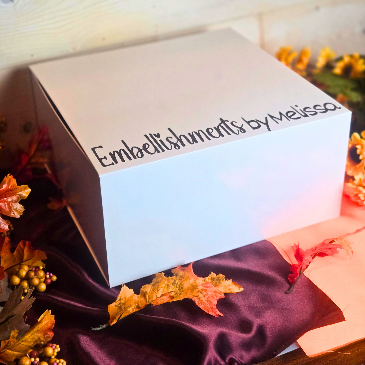 Fall gift box from Embellishments by Melissa surrounded by fall leaves and flowers.