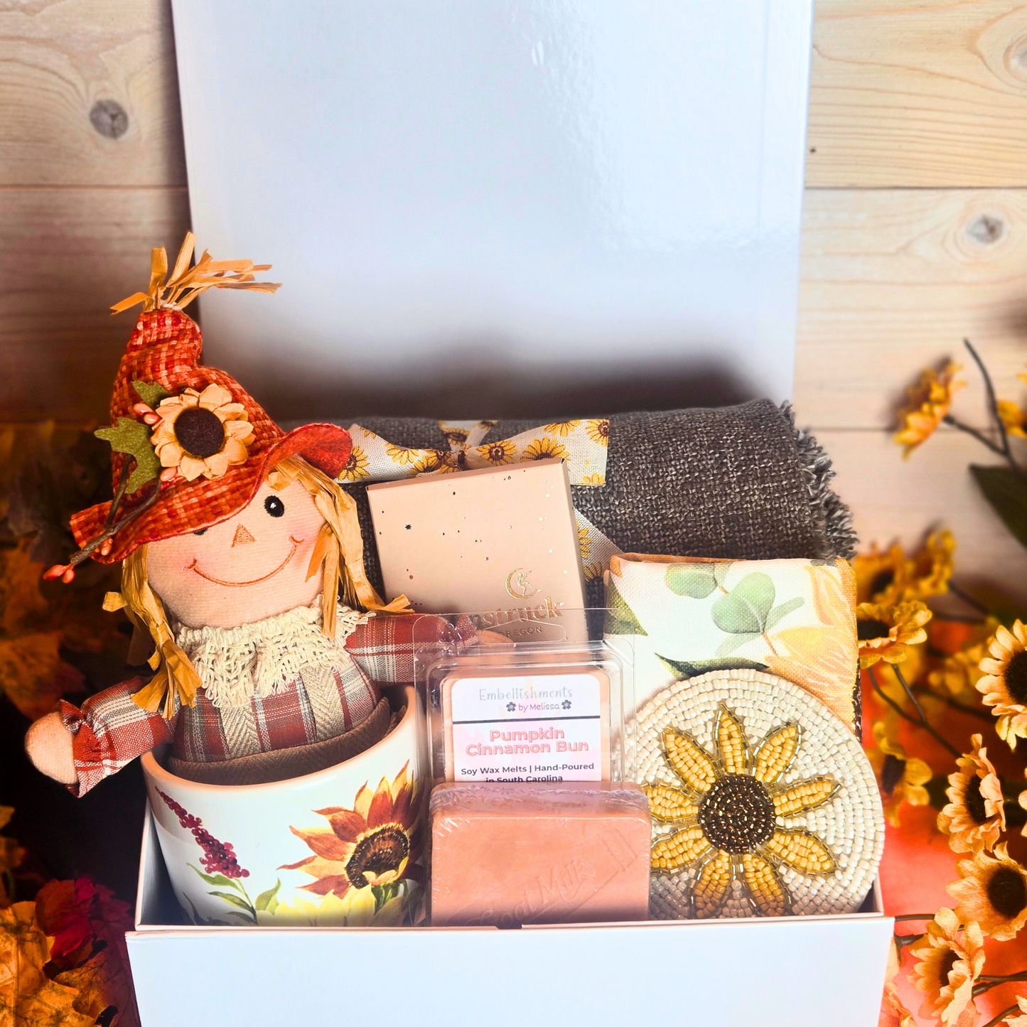 Fall gift box featuring a scarecrow, sunflower mug, and seasonal pumpkin spice treats, front view.