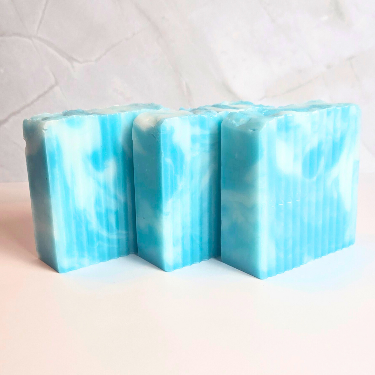 Hand-poured soap featuring a white and turquoise swirl pattern