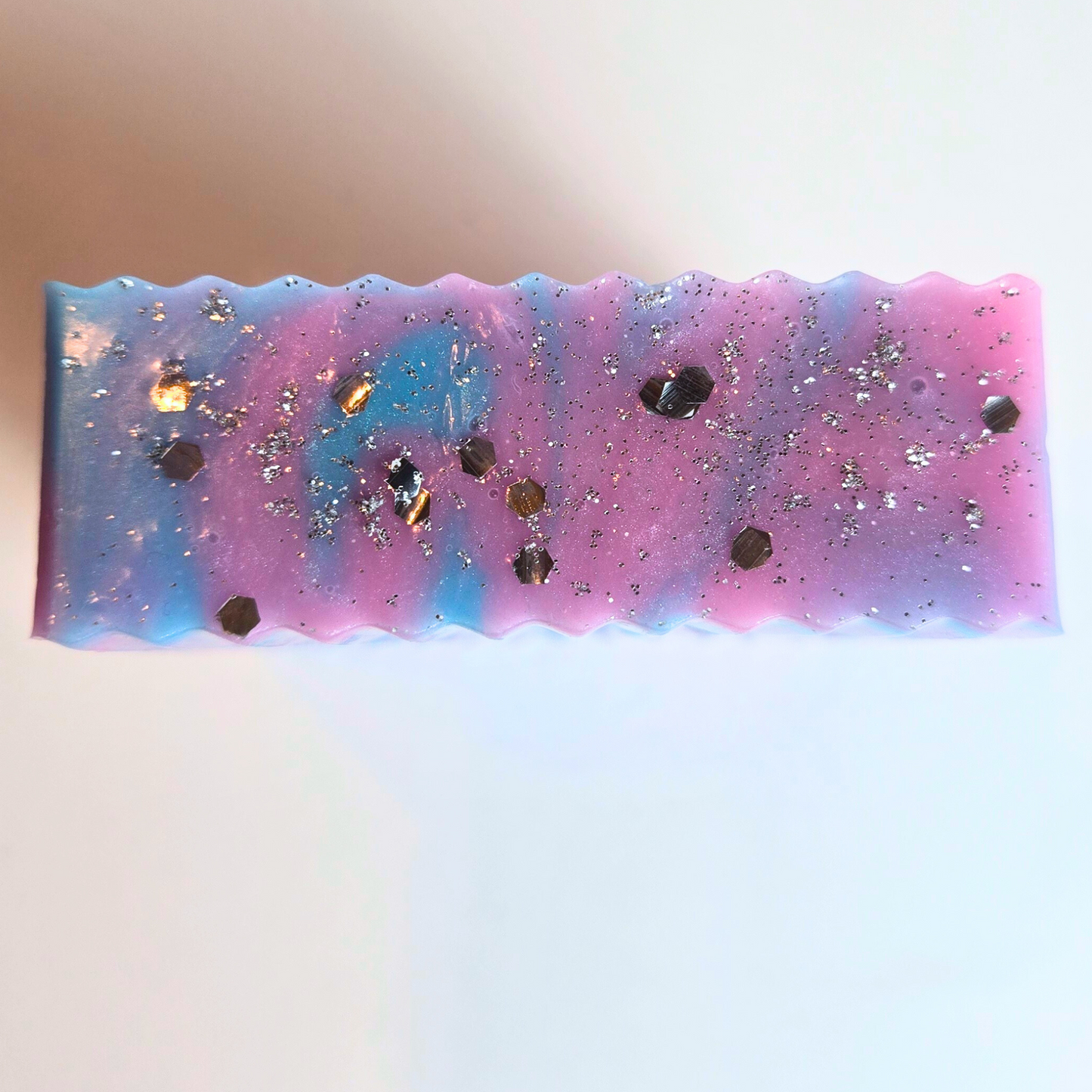 Glittery handcrafted soap in iridescent pastel colors, top view.