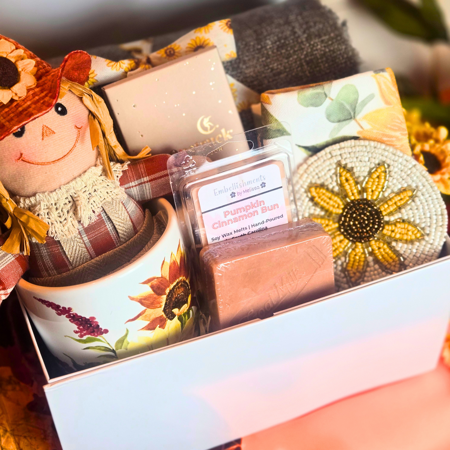 Gift box with decorative items including a sunflower mug, handcrafted pumpkin pie scented soap, and small figurine.