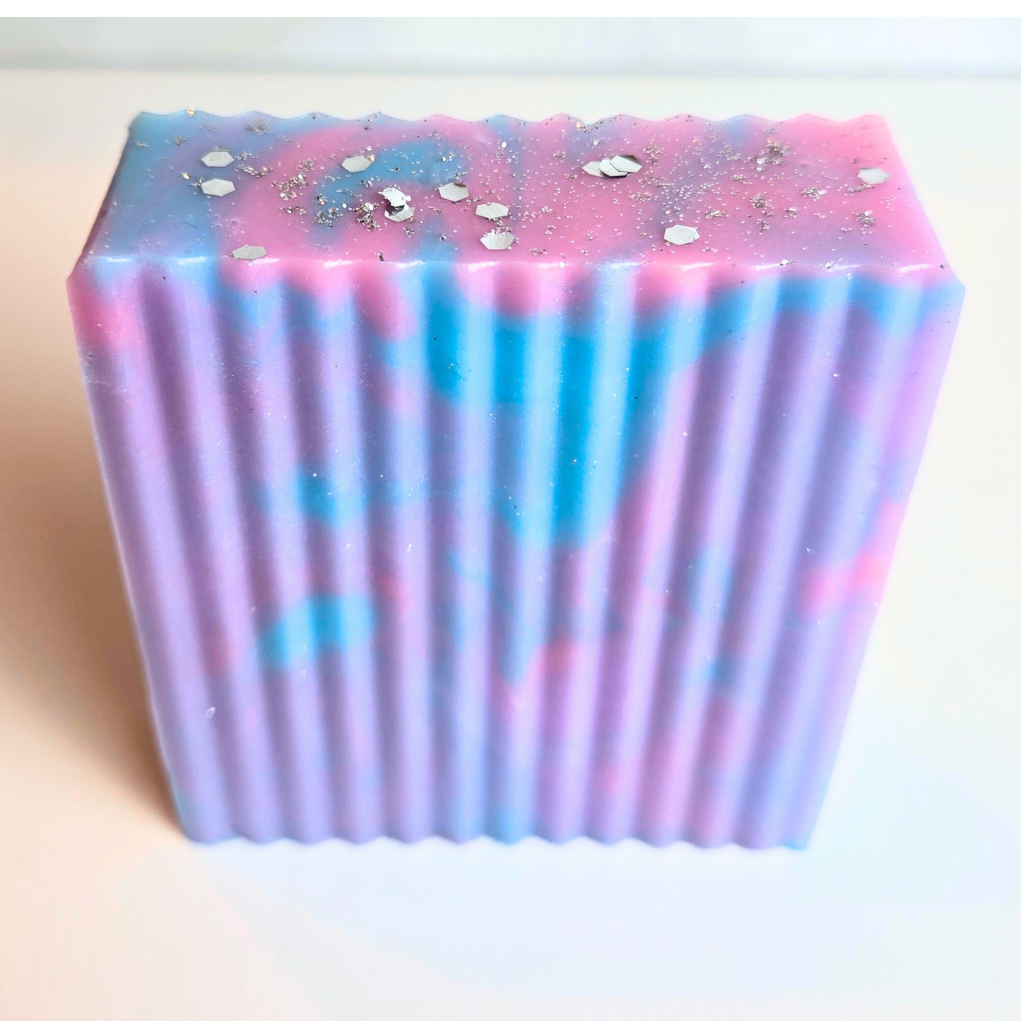 Vibrant sparkly soap bar with handcrafted swirls and glitter, front view.