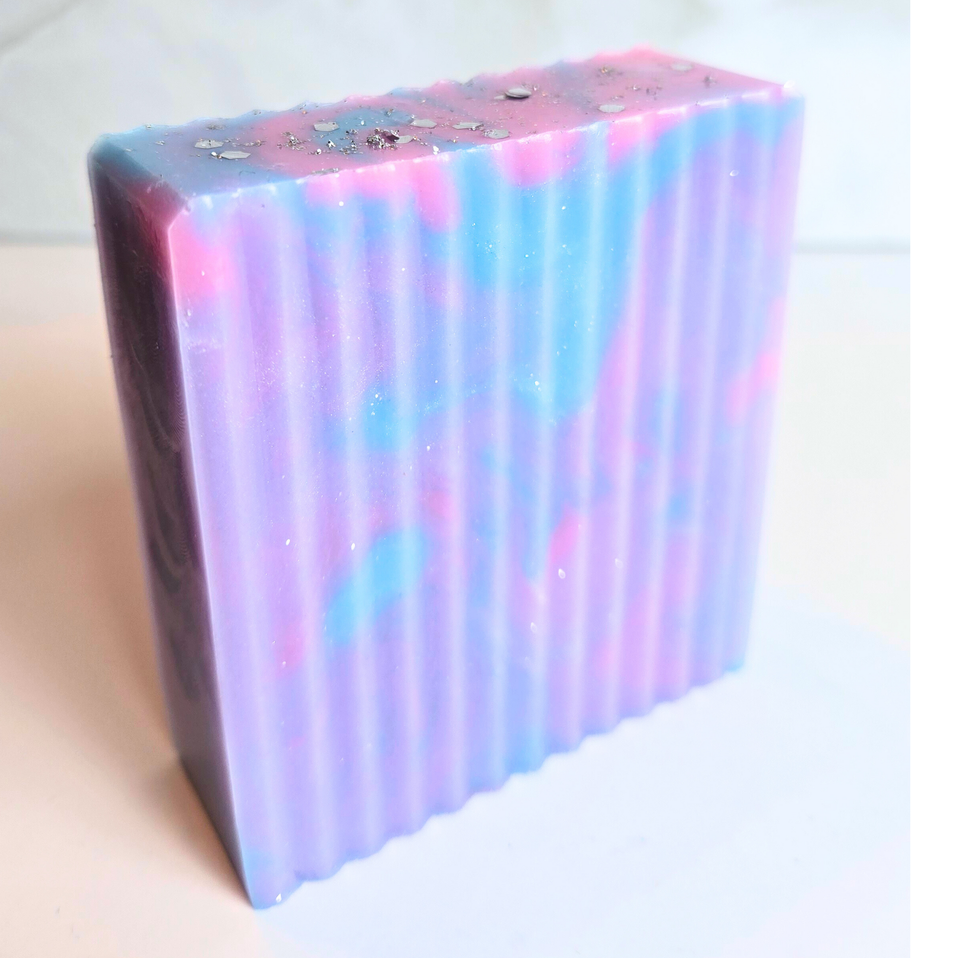 Colorful handmade soap bar with glitter and artistic design, side view.