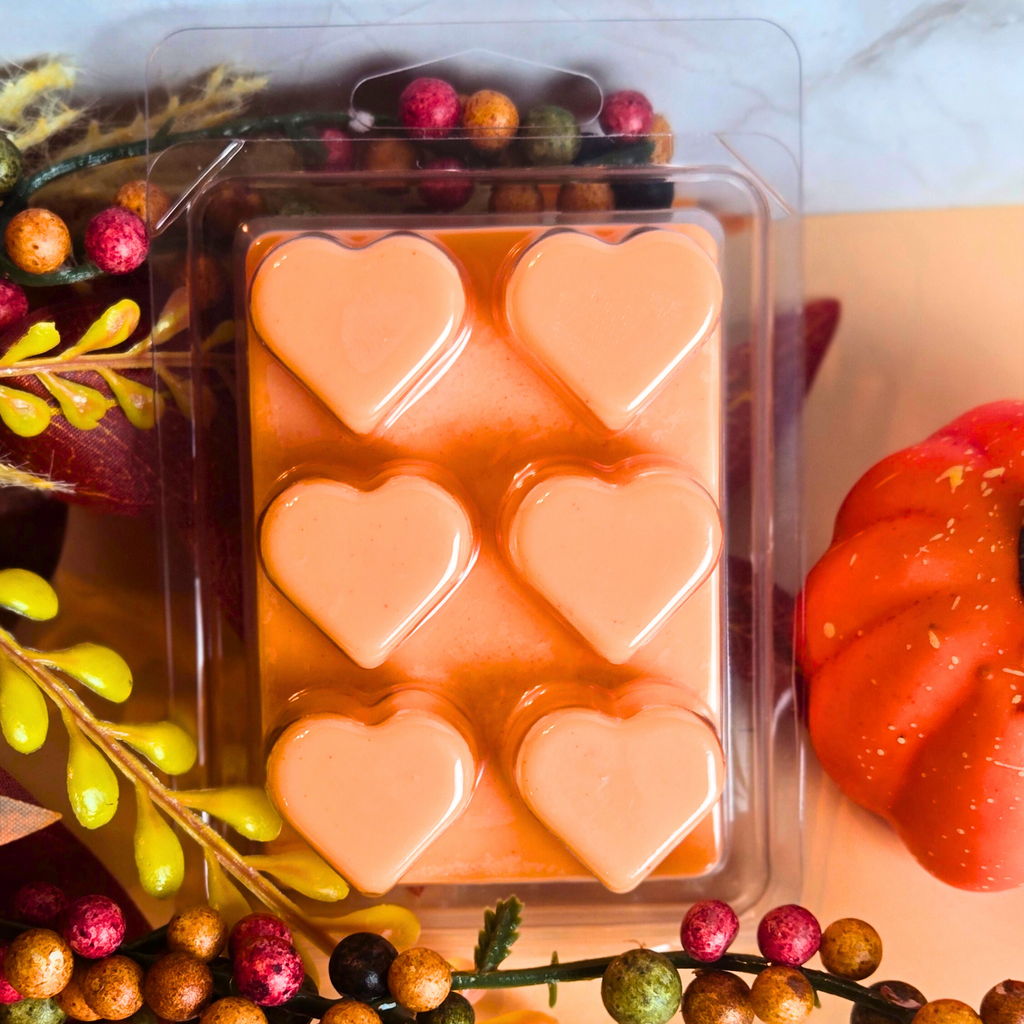 Packaged wax melts with heart shapes on a decorative background with pumpkins and fall decor.