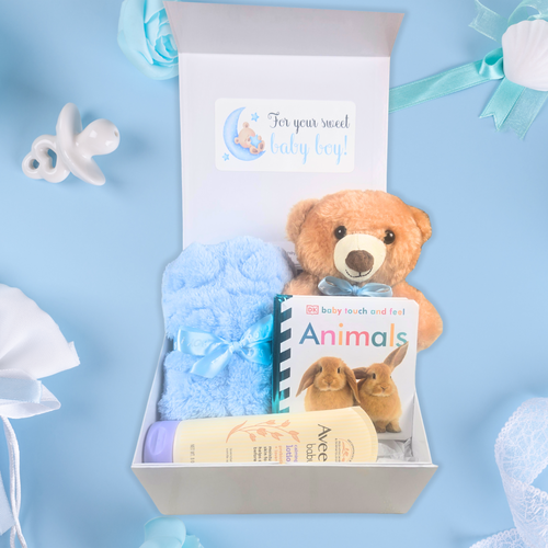 Baby boy gift box with teddy bear, soft blanket, baby lotion, and children's book, front view.