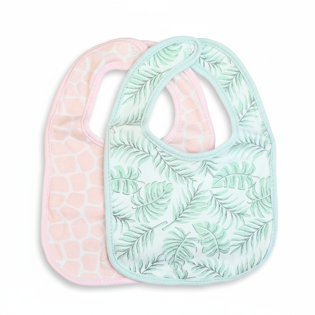 Two baby bibs overlapping on a white background. The front bib is white with a mint green tropical leaf pattern. The other bib has a giraffe spot pattern.