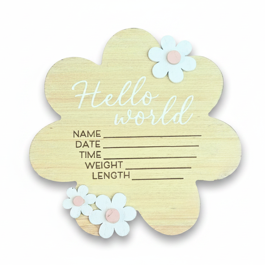 A wooden flower-shaped baby name and date of birth sign with 'Hello world' written on it, decorated with three white paper flowers with pink centers, on a white background.