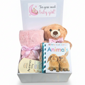 A baby gift box set containing a pink plush blanket tied with a pink ribbon, a brown teddy bear wearing a pink bow, a baby touch and feel Animals book, and an Aveeno baby lotion packet, all arranged inside an open white box.