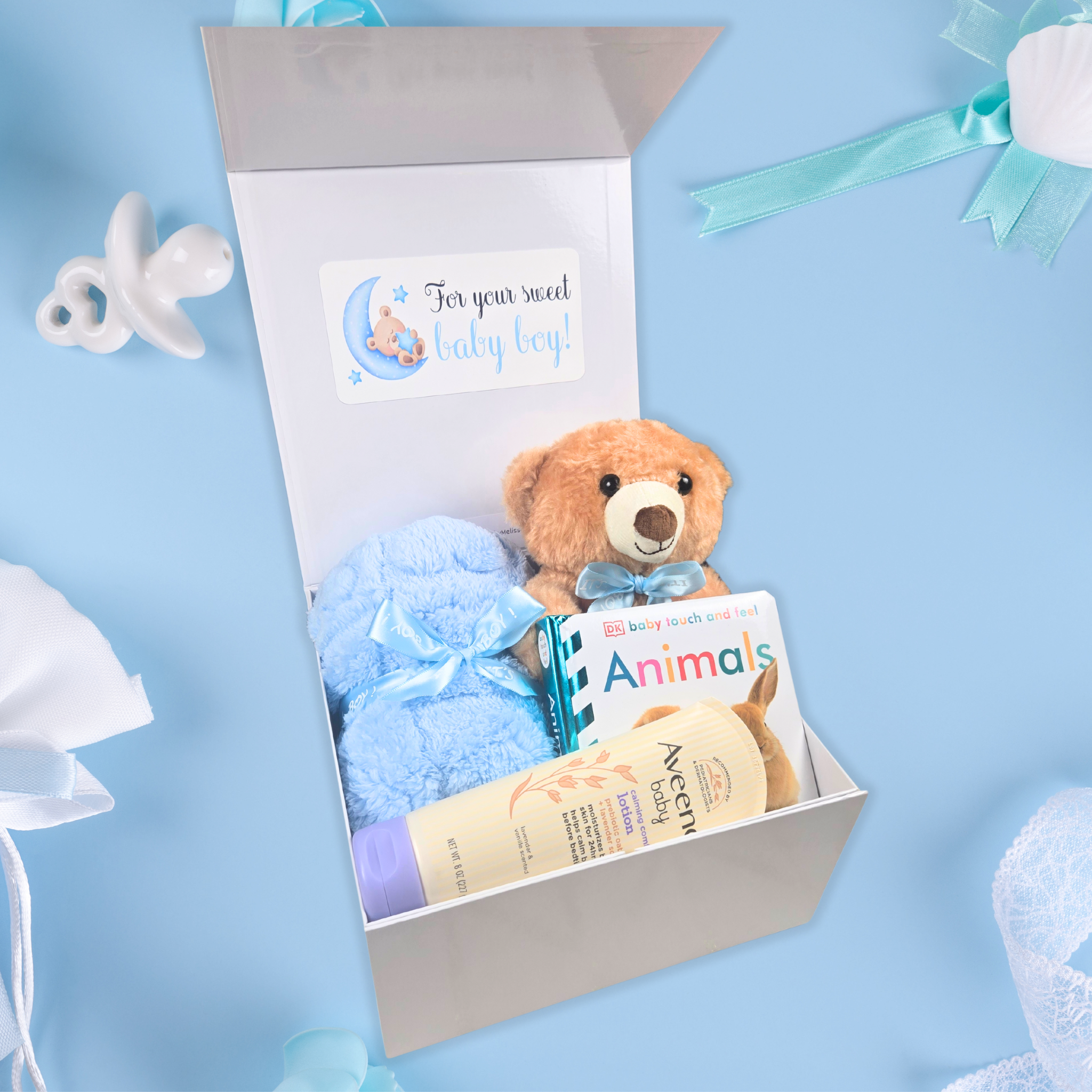 Baby shower gift box for boy featuring teddy bear, lotion, blanket, and book, side view.