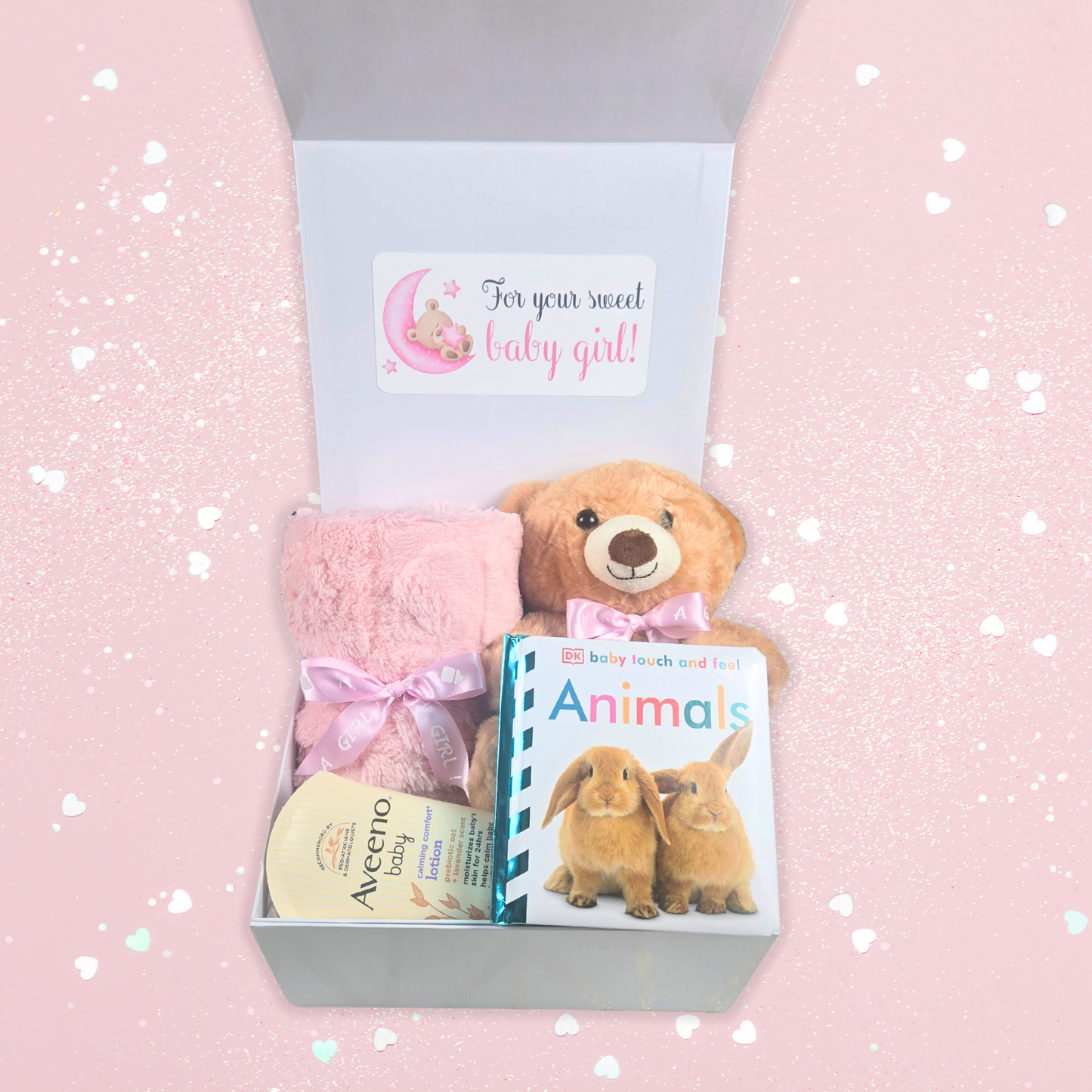 Baby shower gift box for girl including pink baby blanket, bear with pink bow, touch-and-feel book and lavender baby lotion.