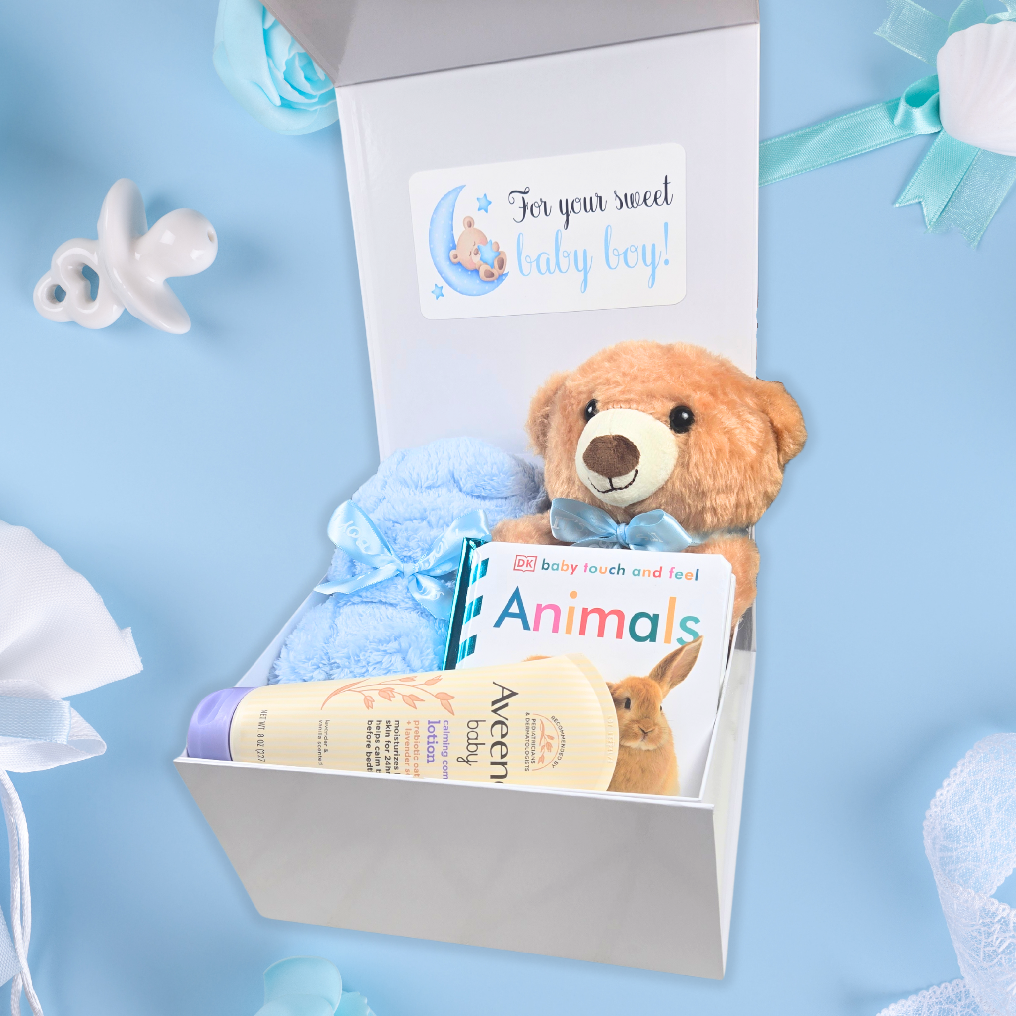 Personalized baby boy gift box with baby's name on the lid, teddy bear, blanket, lotion and book, side view. 