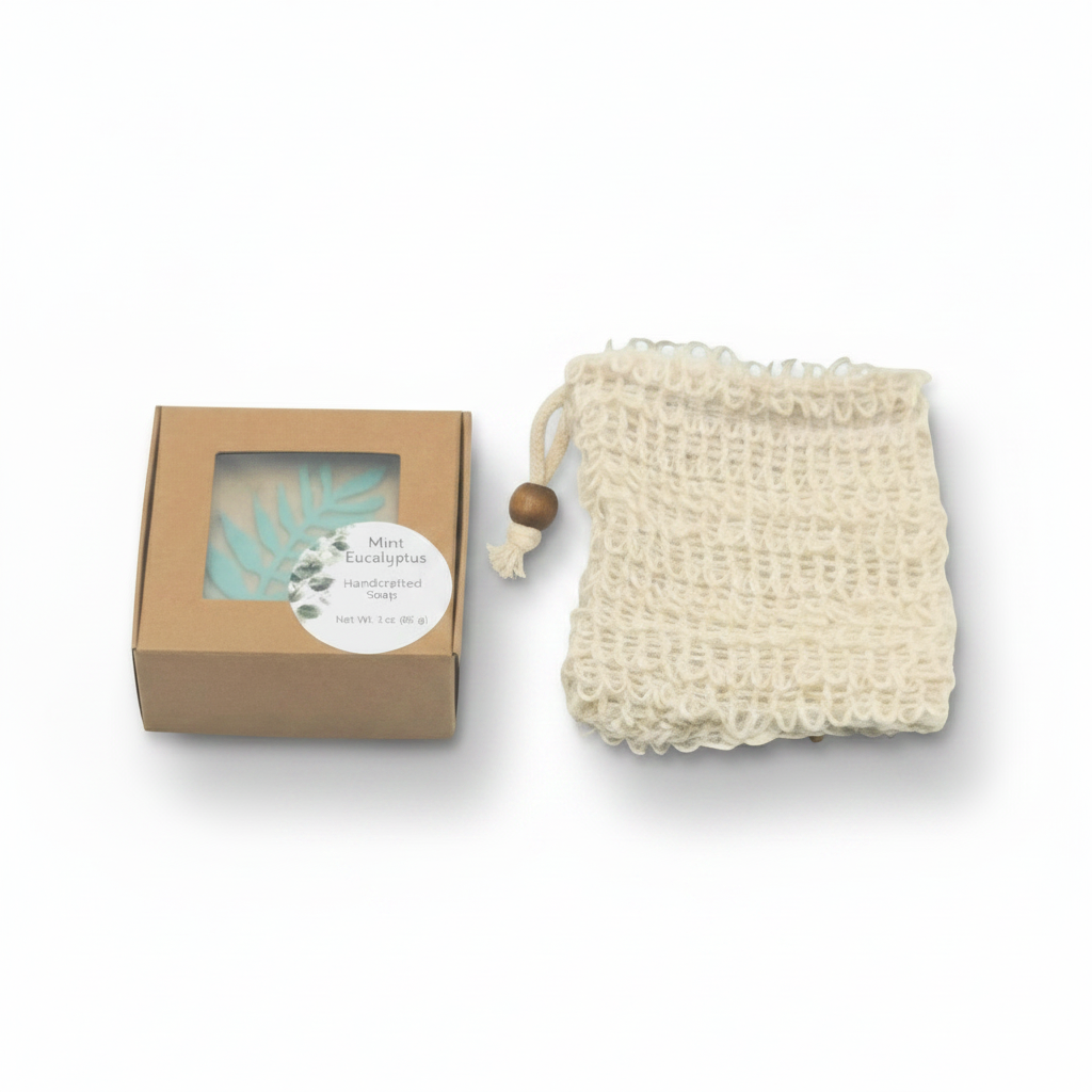 A natural cream-colored cotton mesh soap bag with a wooden bead drawstring next to its brown kraft paper soap bar gift box, shown on a clean white background.