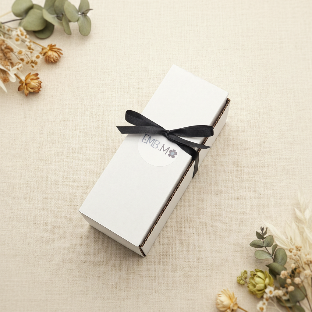White kraft gift box with 3 bath bombs in it , wrapped inblack ribbon on a neutral background.