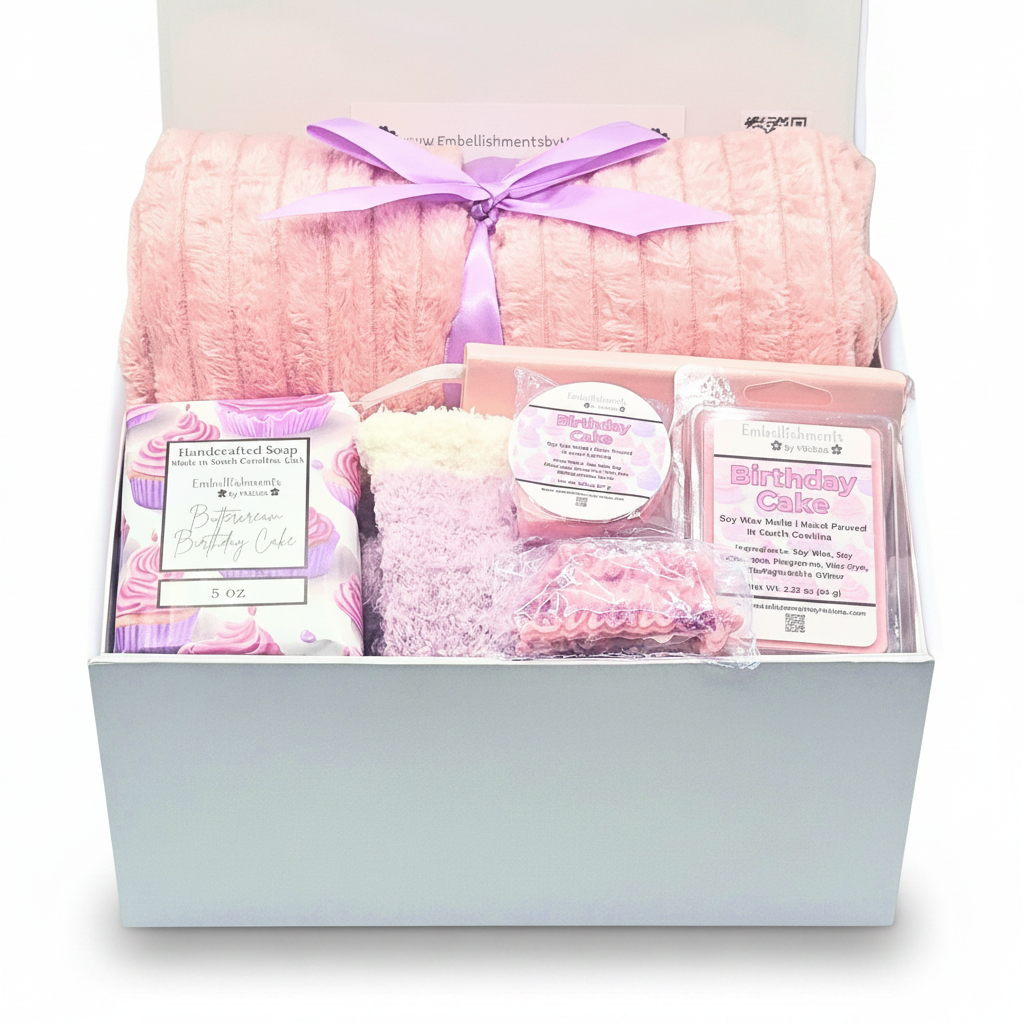 A curated birthday gift box set from The Embellishment Table, featuring a plush pink ribbed blanket tied with a purple ribbon,a pink soap bar, wax melts and cozy socks.