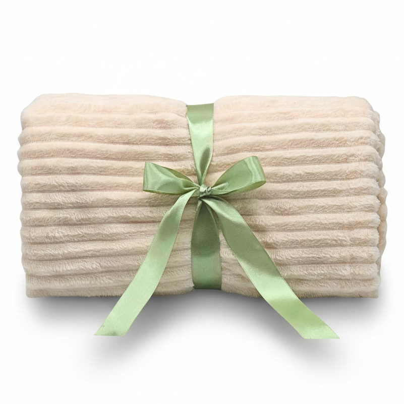 A folded cream-colored ribbed plush blanket tied with a light green satin ribbon bow, shown on a clean white background.