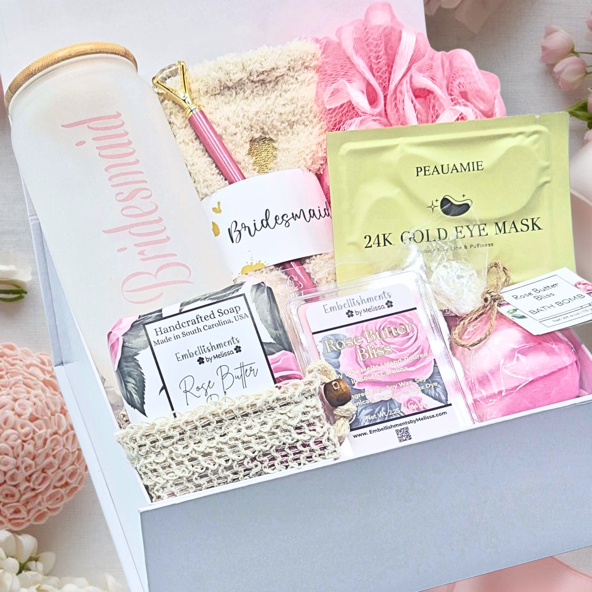 Gift box with various items including a gold eye mask, soap, and a tumbler with Bridesmaid text.