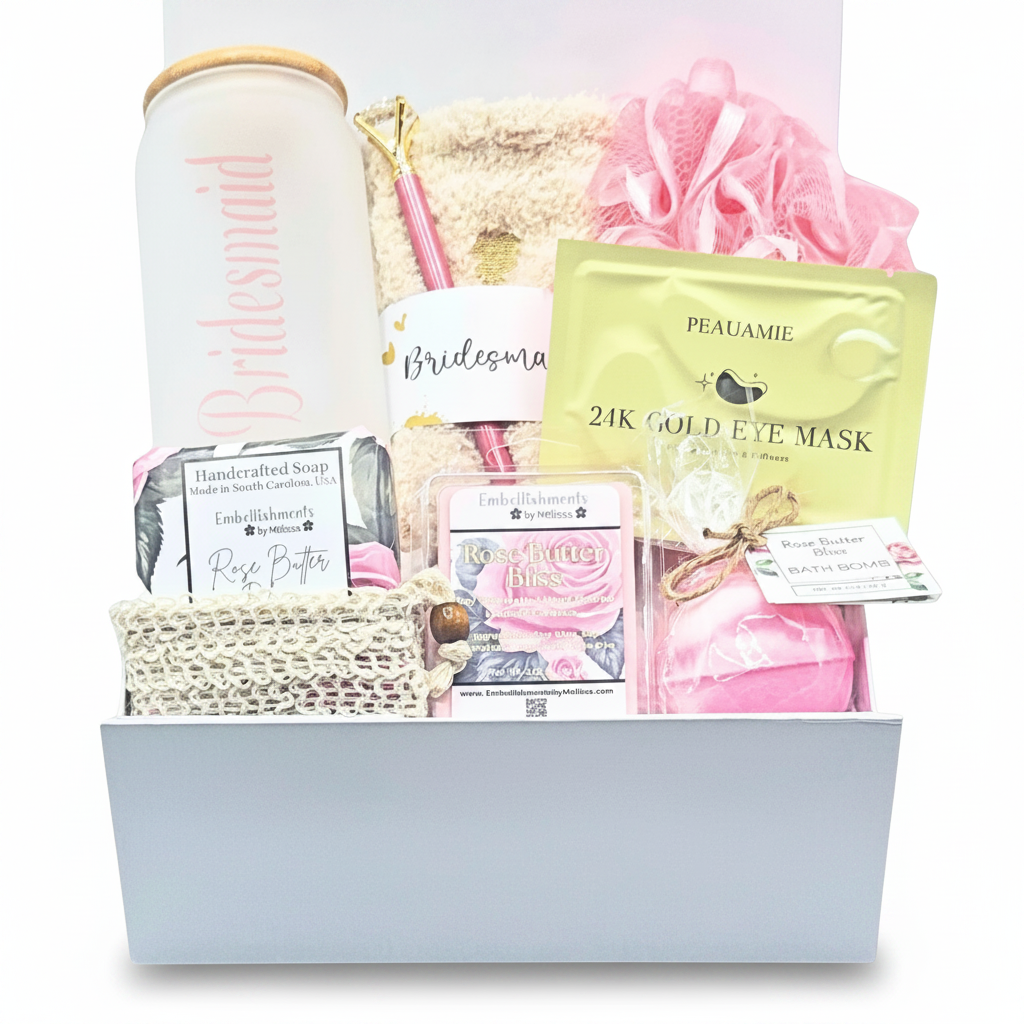 A bridal shower gift basket filled with various pampering items including a sipper glass labeled 'Bridesmaid', a gold packet of '21K GOLD EYE MASK', pink pouf, rose soap with soap saver bag, and a rose bath bomb, all arranged in a white magnetic box.