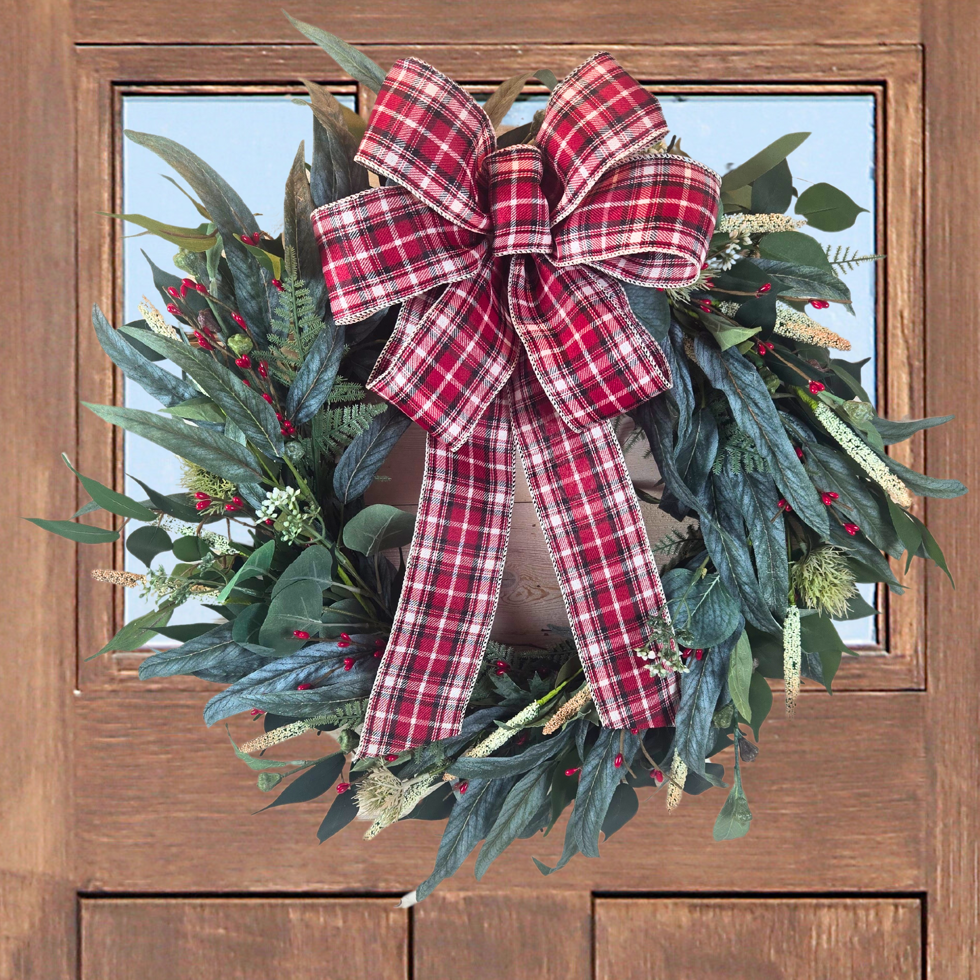 Christmas wreath with red berries and buffalo plaid bow.