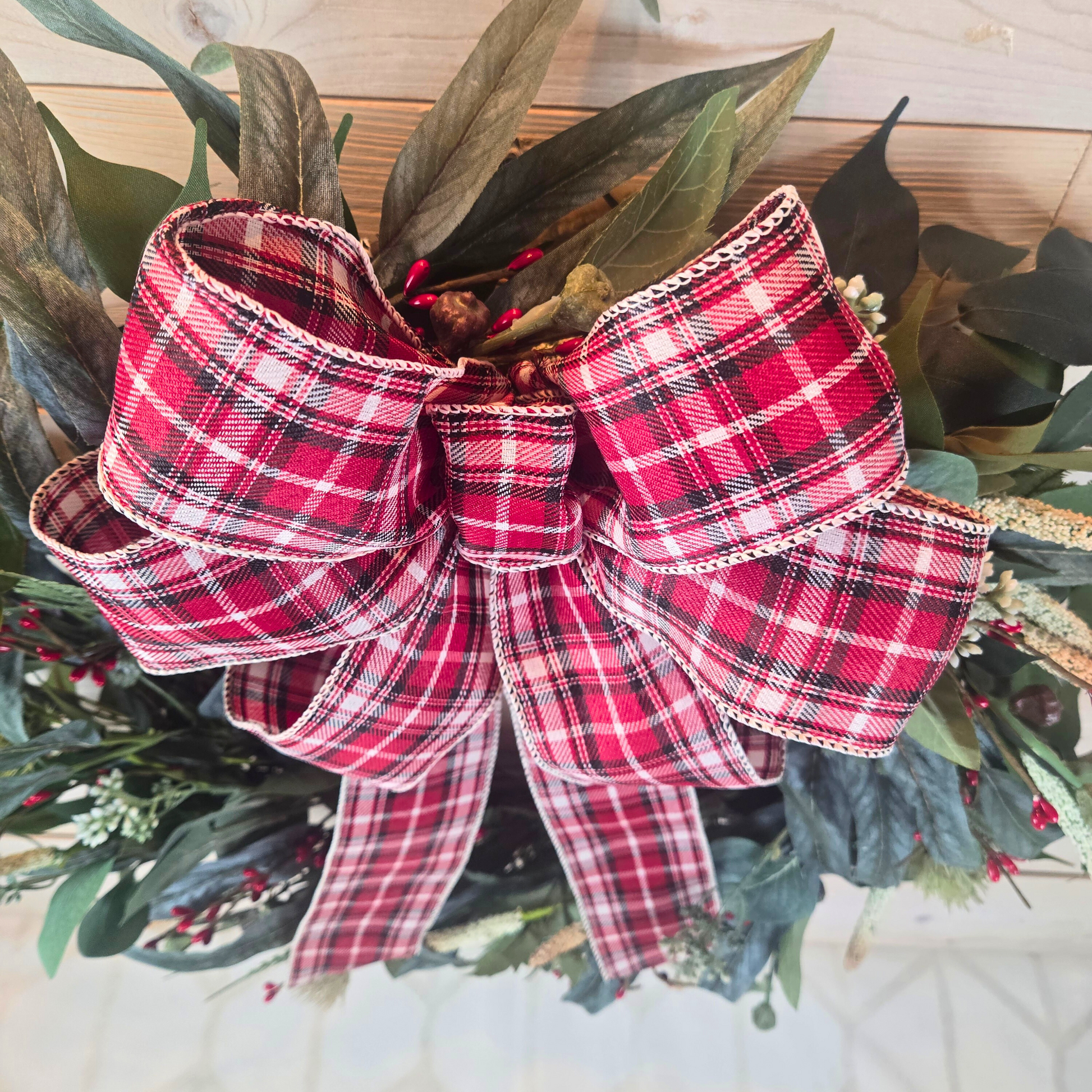 Christmas wreath with red berries and buffalo plaid bow.