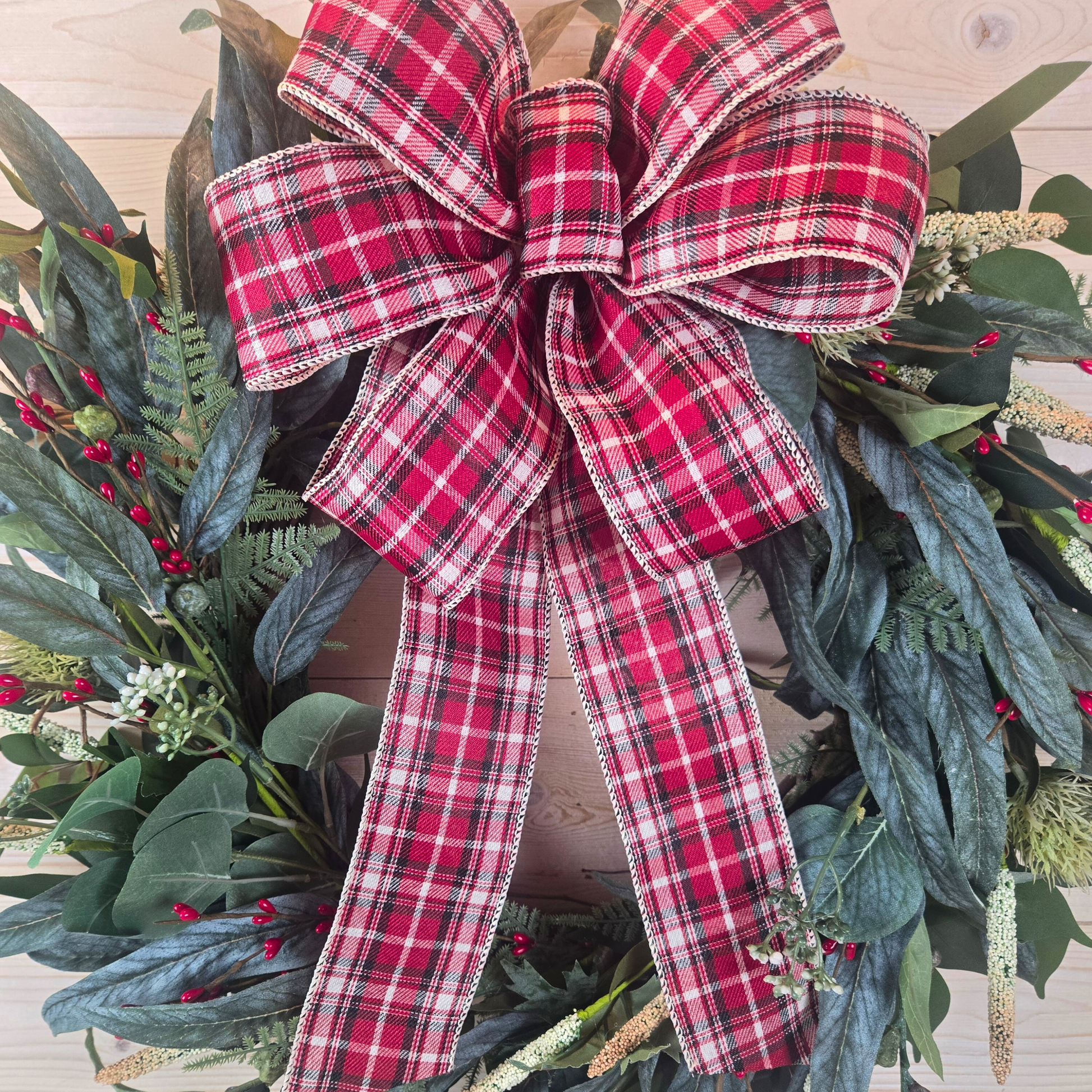 Christmas wreath with red berries and buffalo plaid bow.