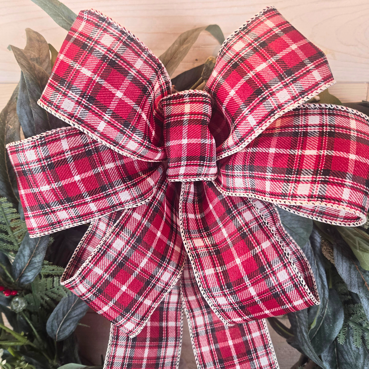 Christmas wreath with red berries and buffalo plaid bow.