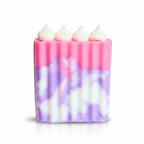 Artisan soap resembling a birthday cake in pink and purple hues, front view.