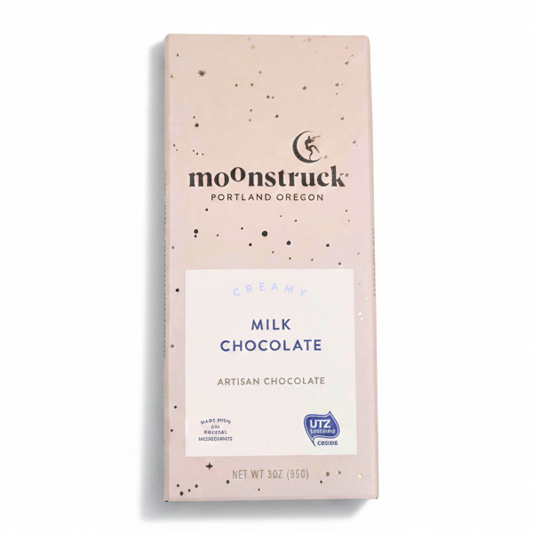 A 3 oz bar of Moonstruck Creamy Milk Chocolate in a beige speckled package, shown on a clean white background.