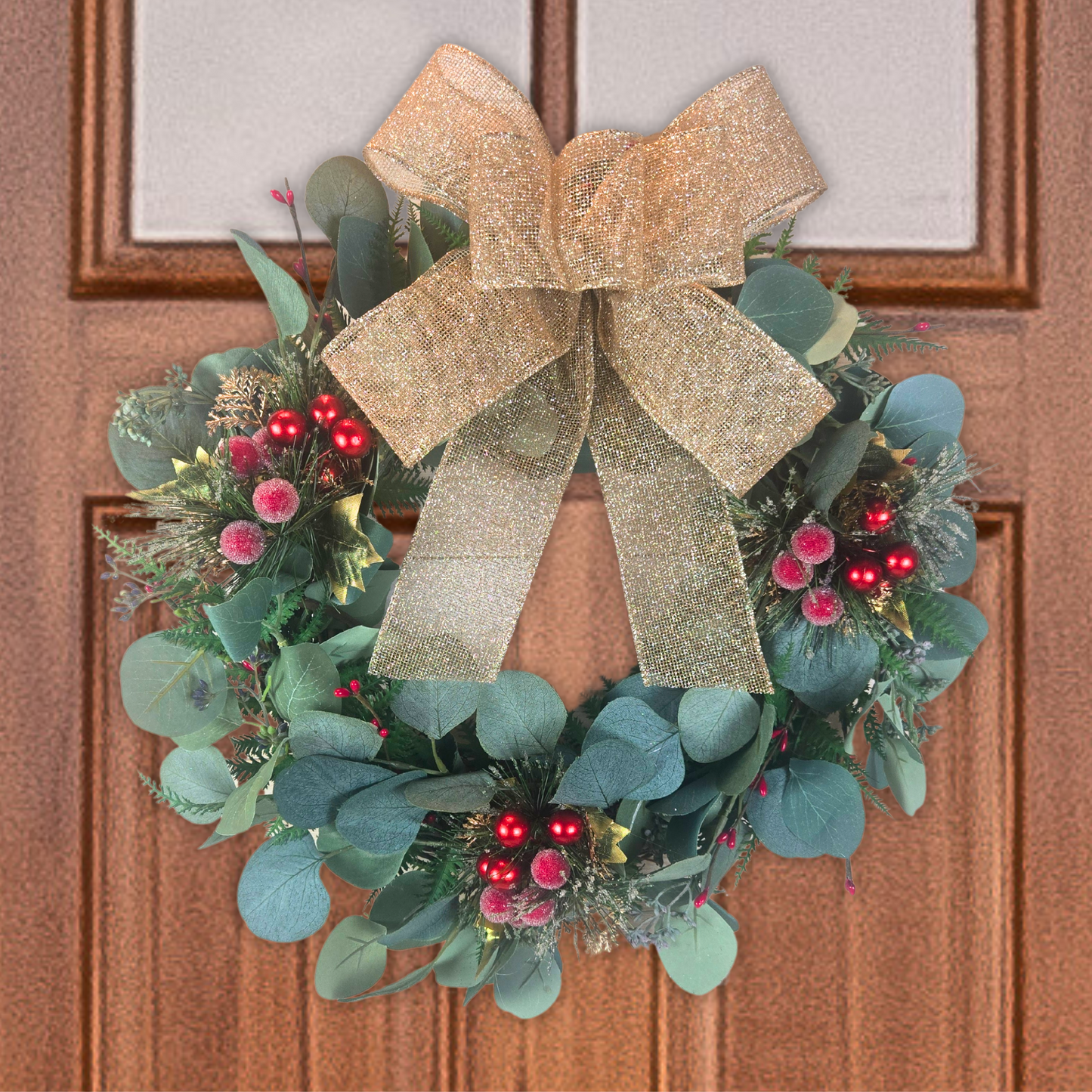 Christmas wreath with red berries and gold bow for front door.