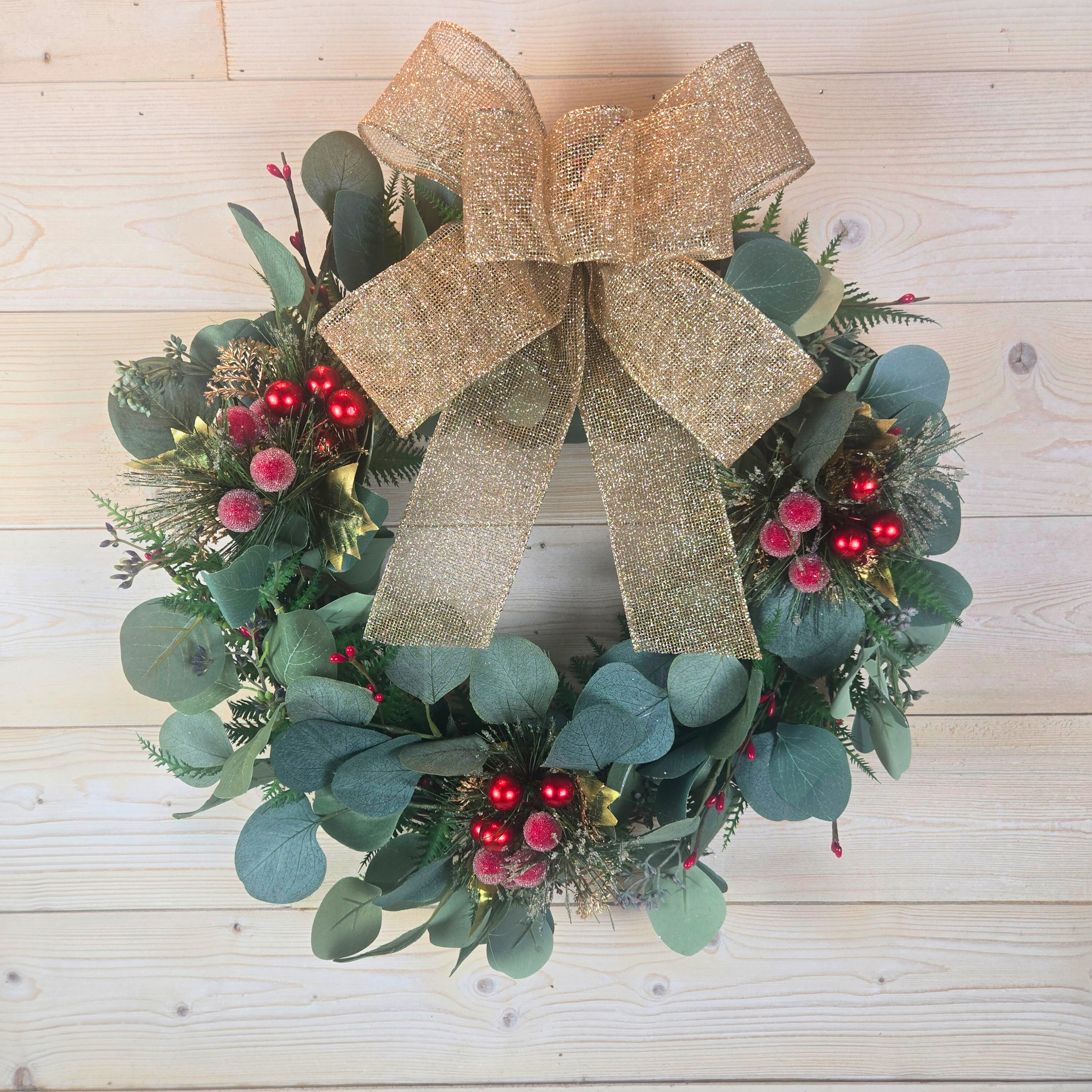 Christmas wreath with red berries and gold bow for front door.