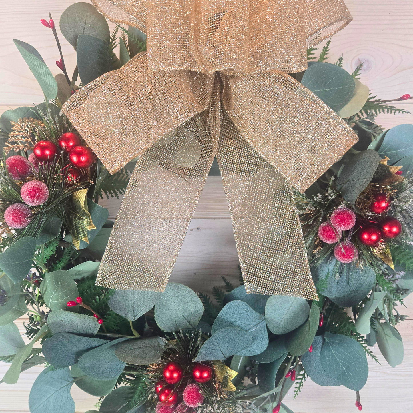 Christmas wreath with red berries and gold bow for front door.