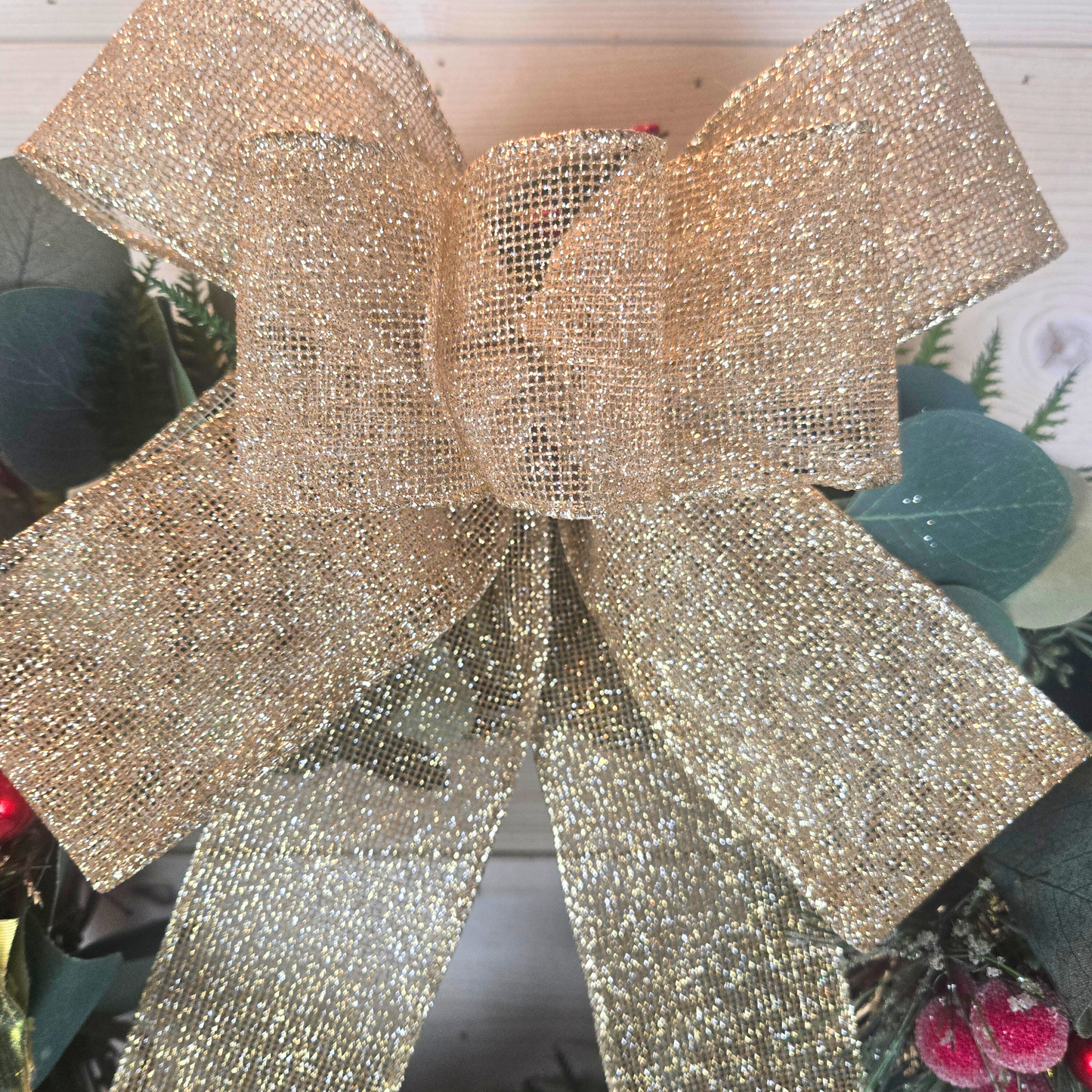 Christmas wreath with red berries and gold bow for front door.