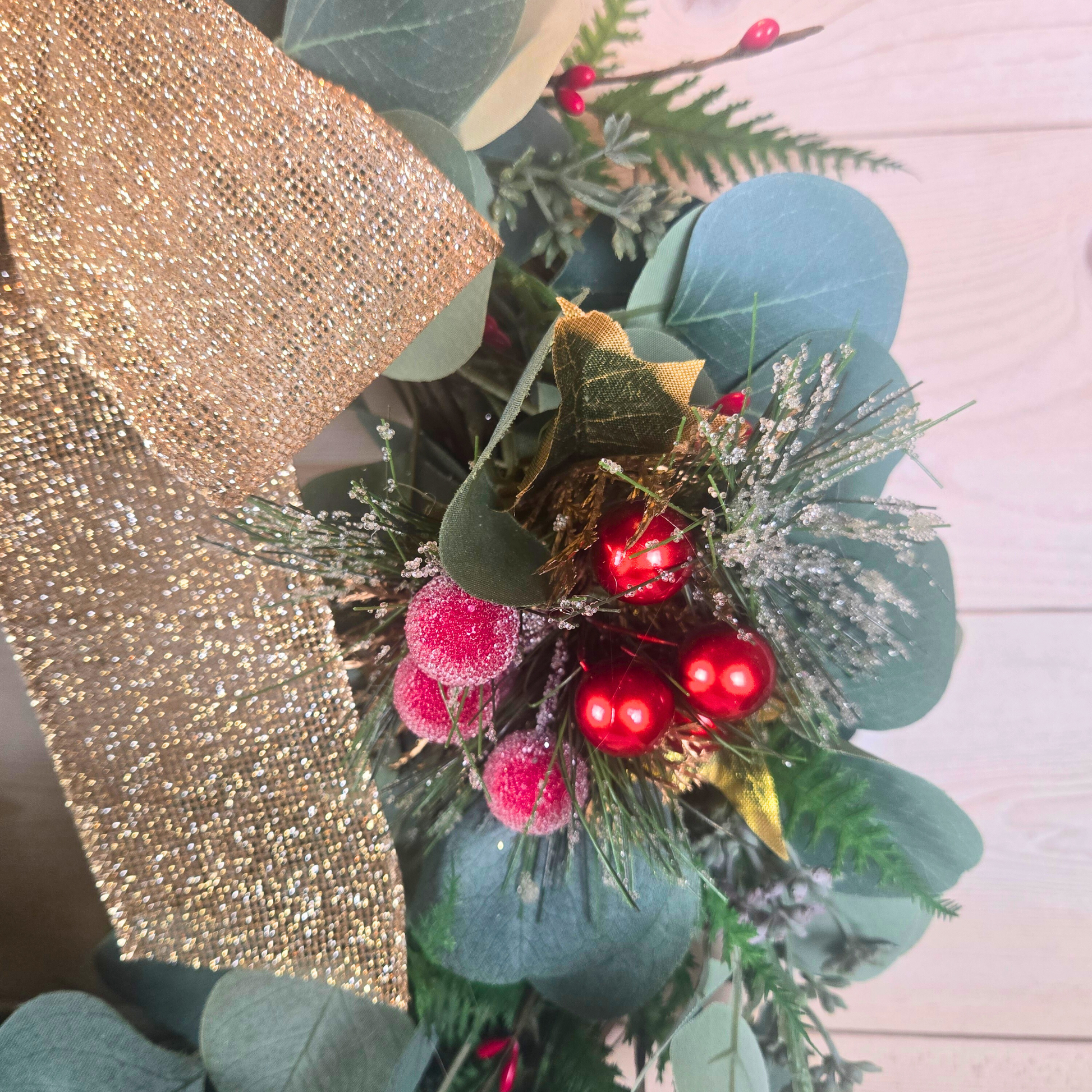 Christmas wreath with red berries and gold bow for front door.