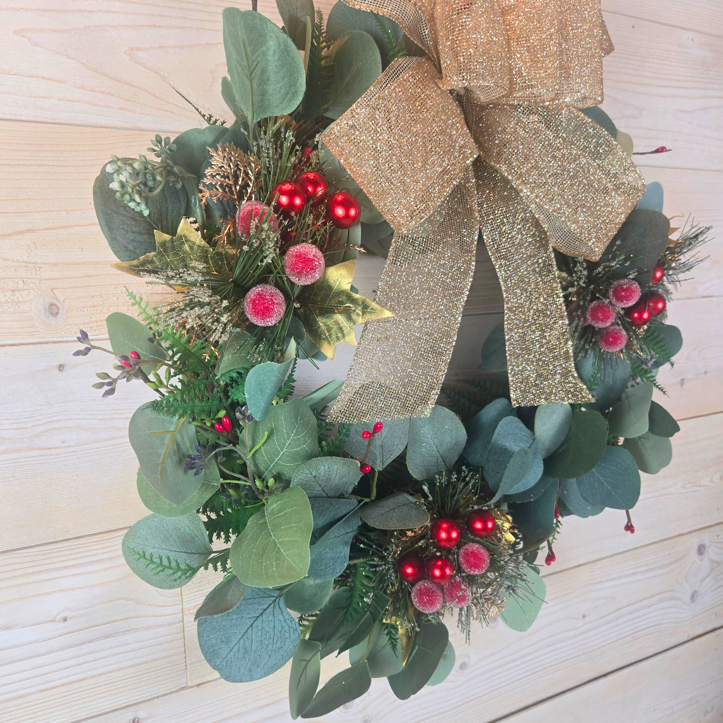 Christmas wreath with red berries and gold bow for front door.