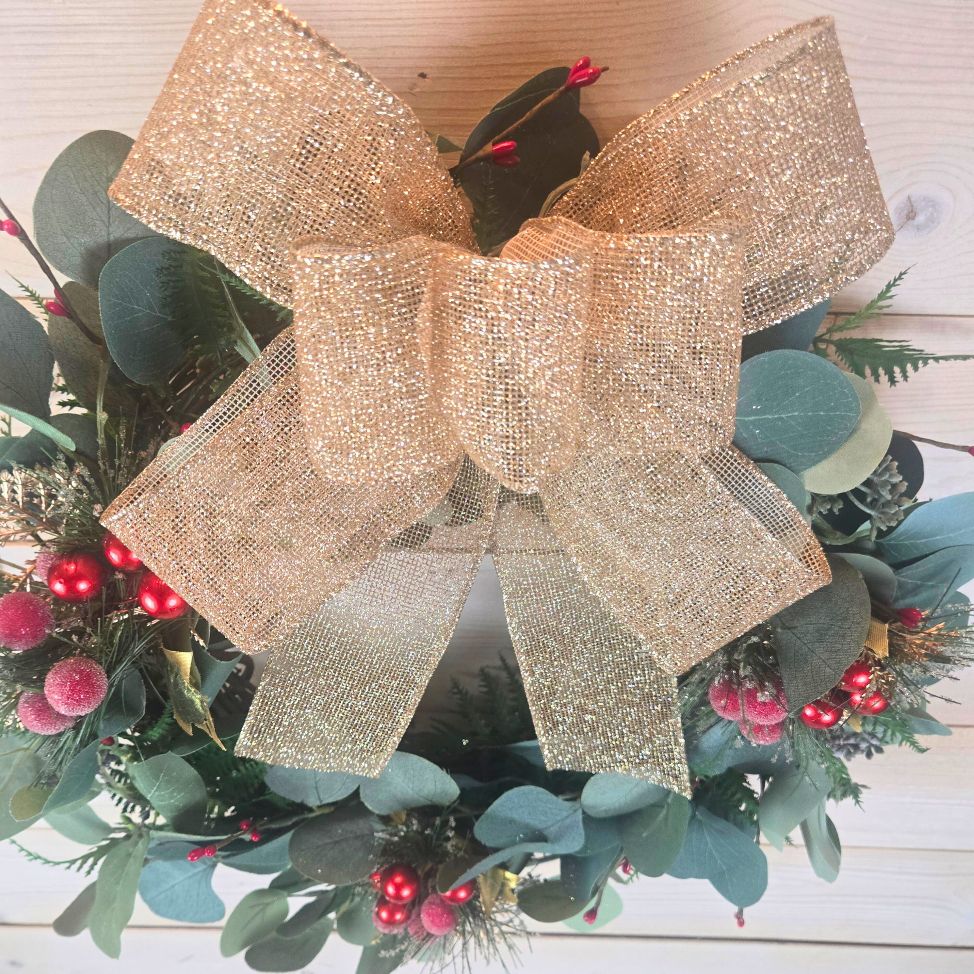 Christmas wreath with red berries and gold bow for front door.