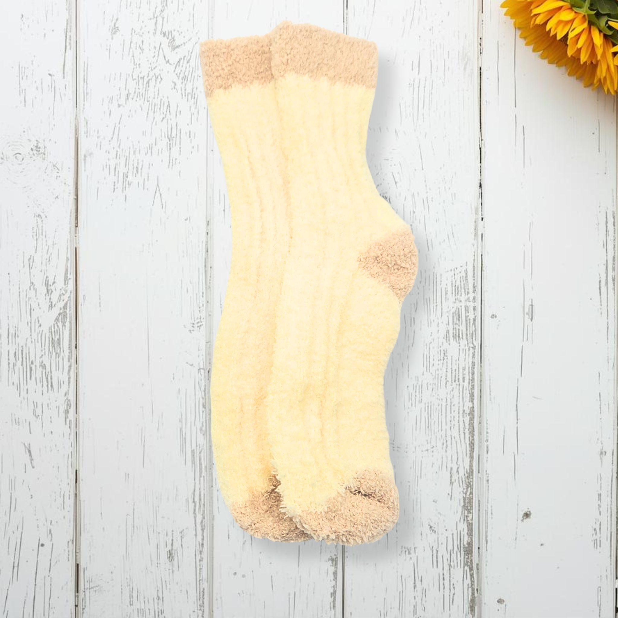 Yellow sock with brown trim on a white wooden surface