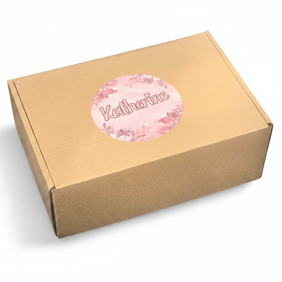 A square kraft paper box with a round pink floral sticker on top that reads 'Katherine' in script, shown on a clean white background.