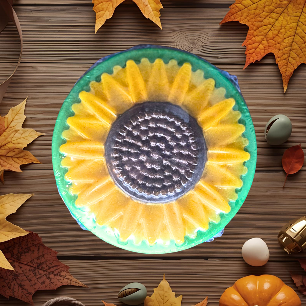 Decorative handcrafted sunflower soap with autumn leaves and pumpkins on a wooden surface
