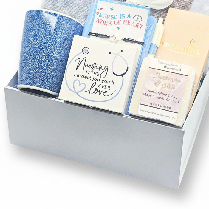 A gift box containing a blue mug, a bracelet, a soap bar, and other small gift items arranged in a white box.