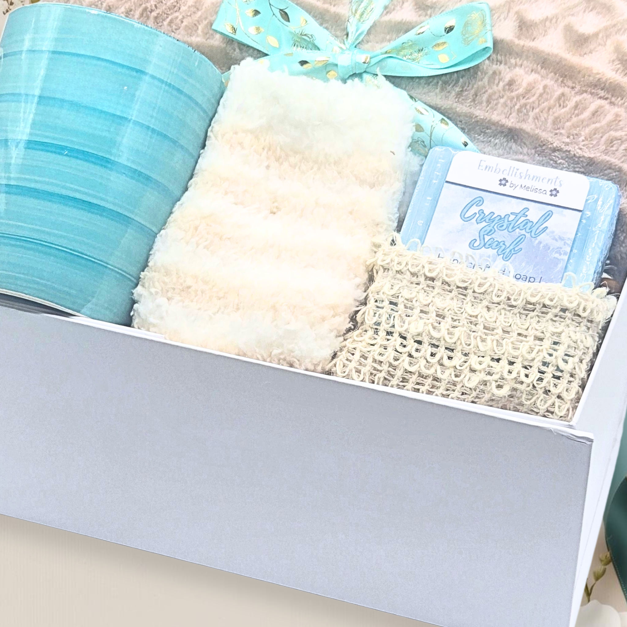Gift box with textured items and a blue ribbon on a neutral background