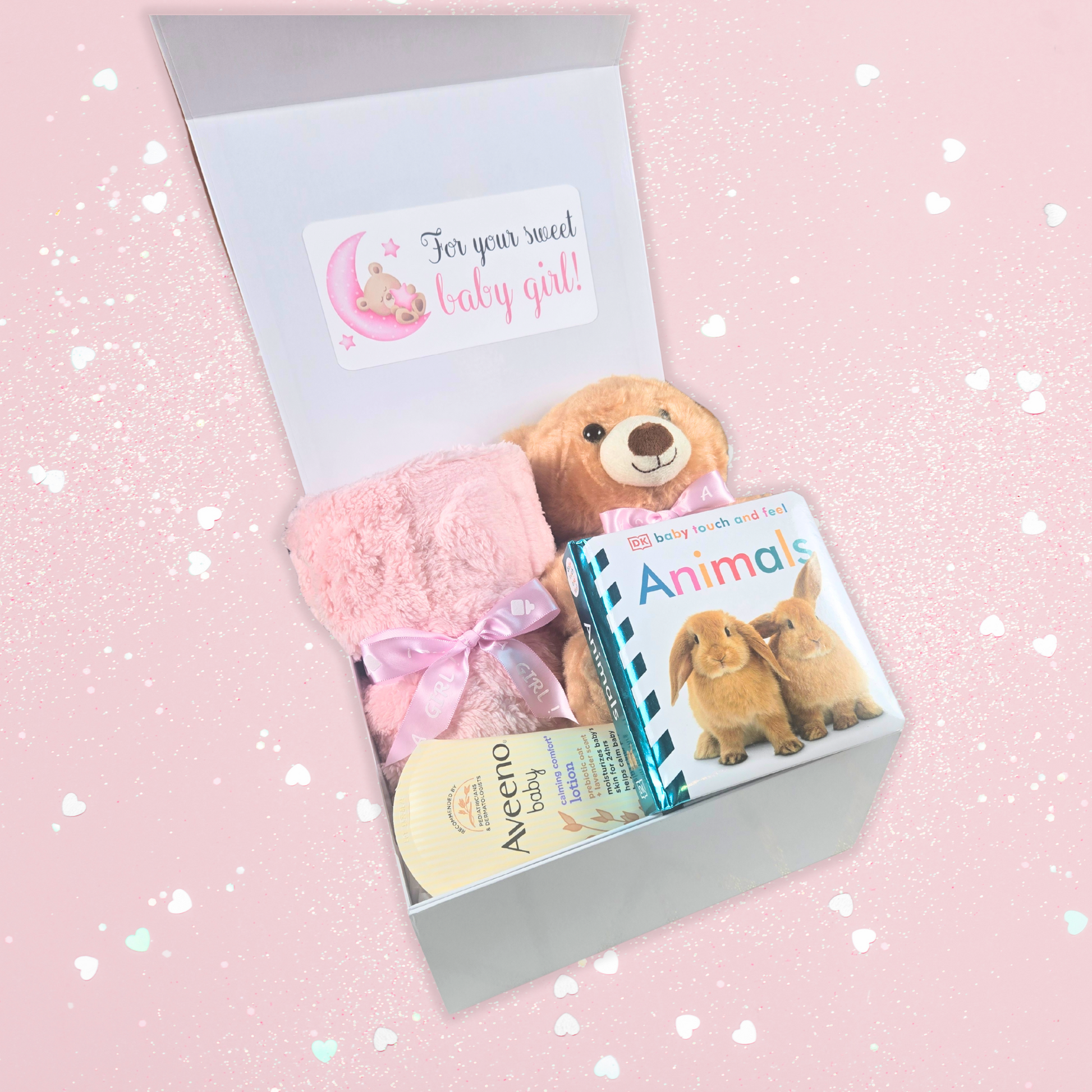 Baby shower gift box for girl including pink baby blanket, bear with pink bow, touch-and-feel book and lavender baby lotion.