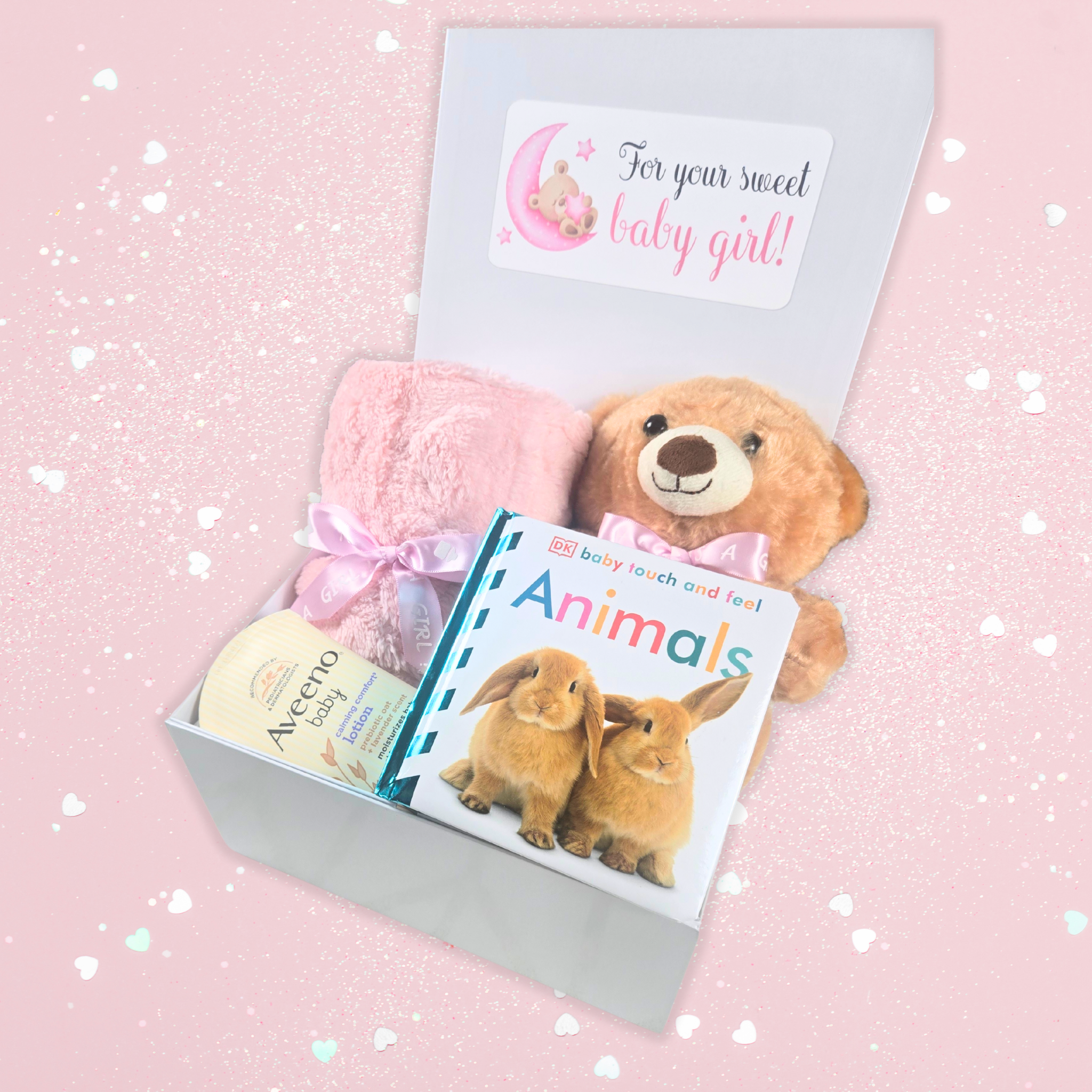 Personalized pink gift box for baby girl with teddy bear, blanket, lotion, and book side view.