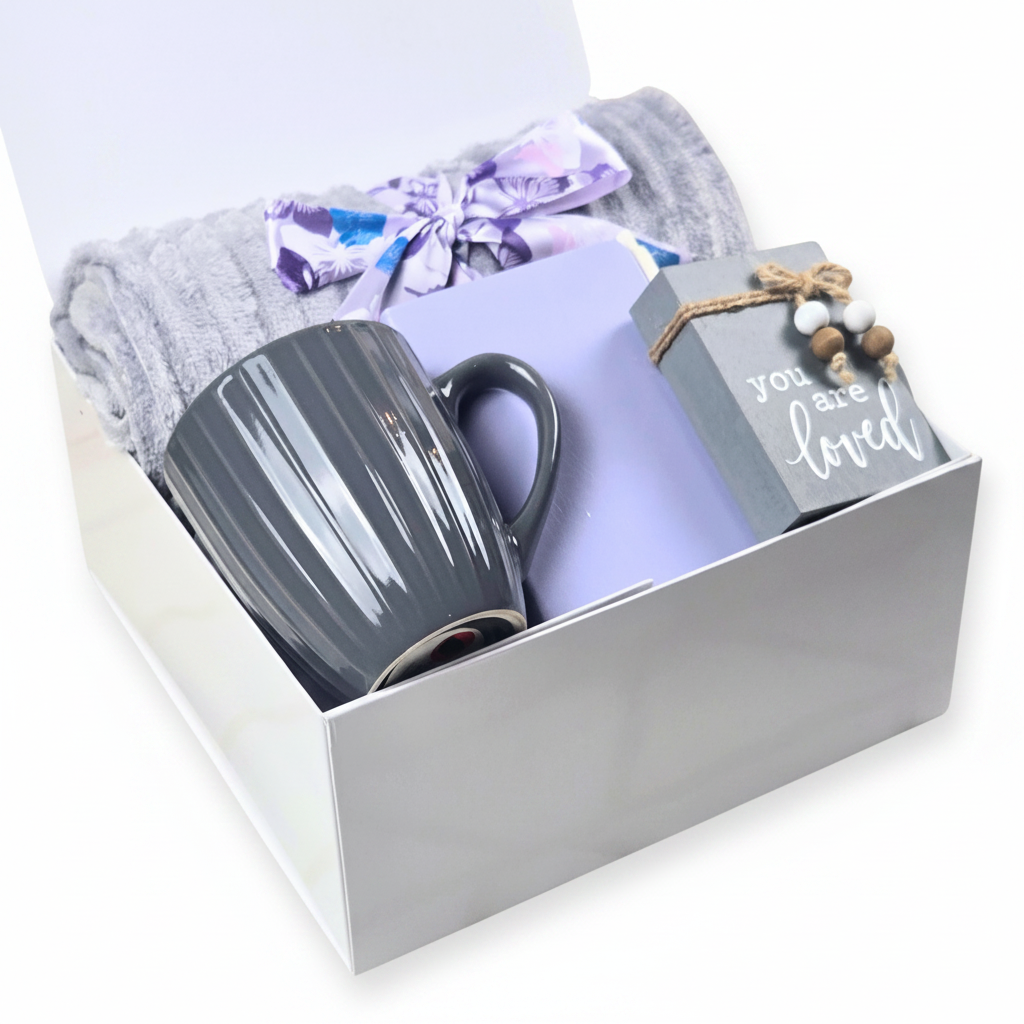 Self-care gift set including throw, notebook, pen, coffee mug, and affirmation sign on white surface.