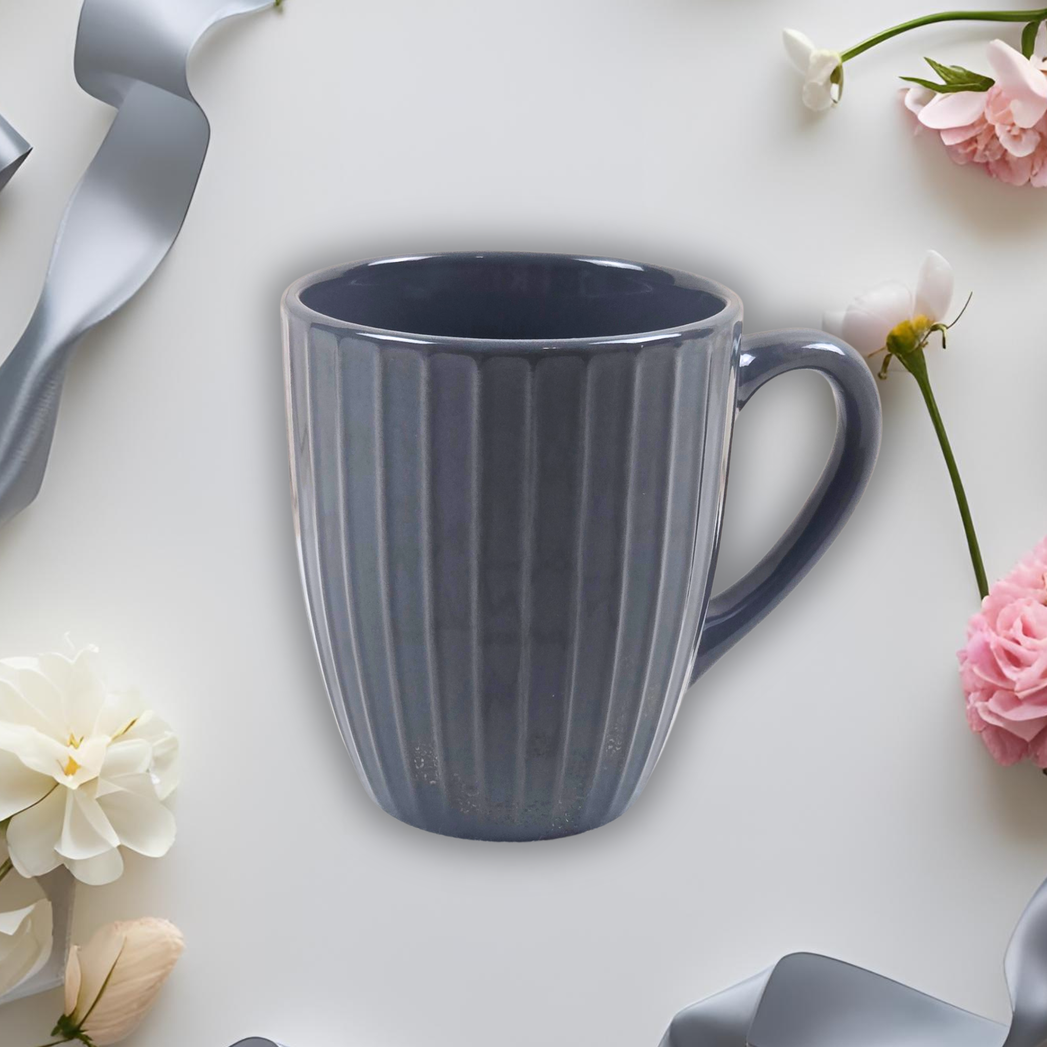 Grey mug on a light-colored surface with flowers and ribbons