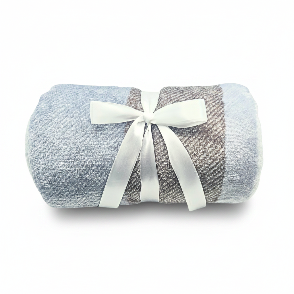 A rolled textured blanket in light blue and taupe-gray, tied with a white satin bow, displayed on a white surface.