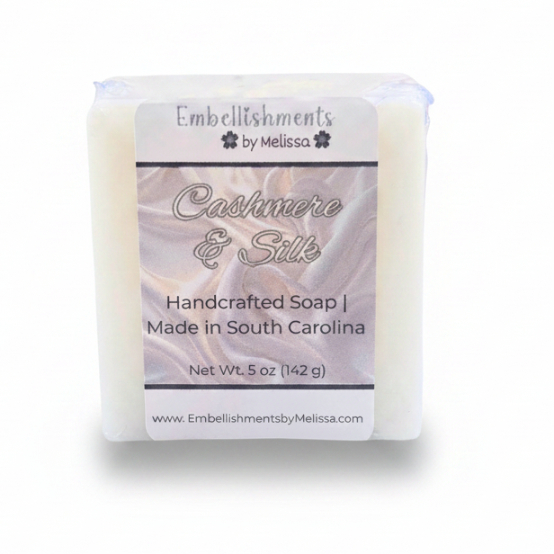 A rectangular bar of handcrafted soap wrapped in clear plastic with a white paper label reading 'Embellishments by Melissa' and 'Cashmere & Silk,' on a white background.