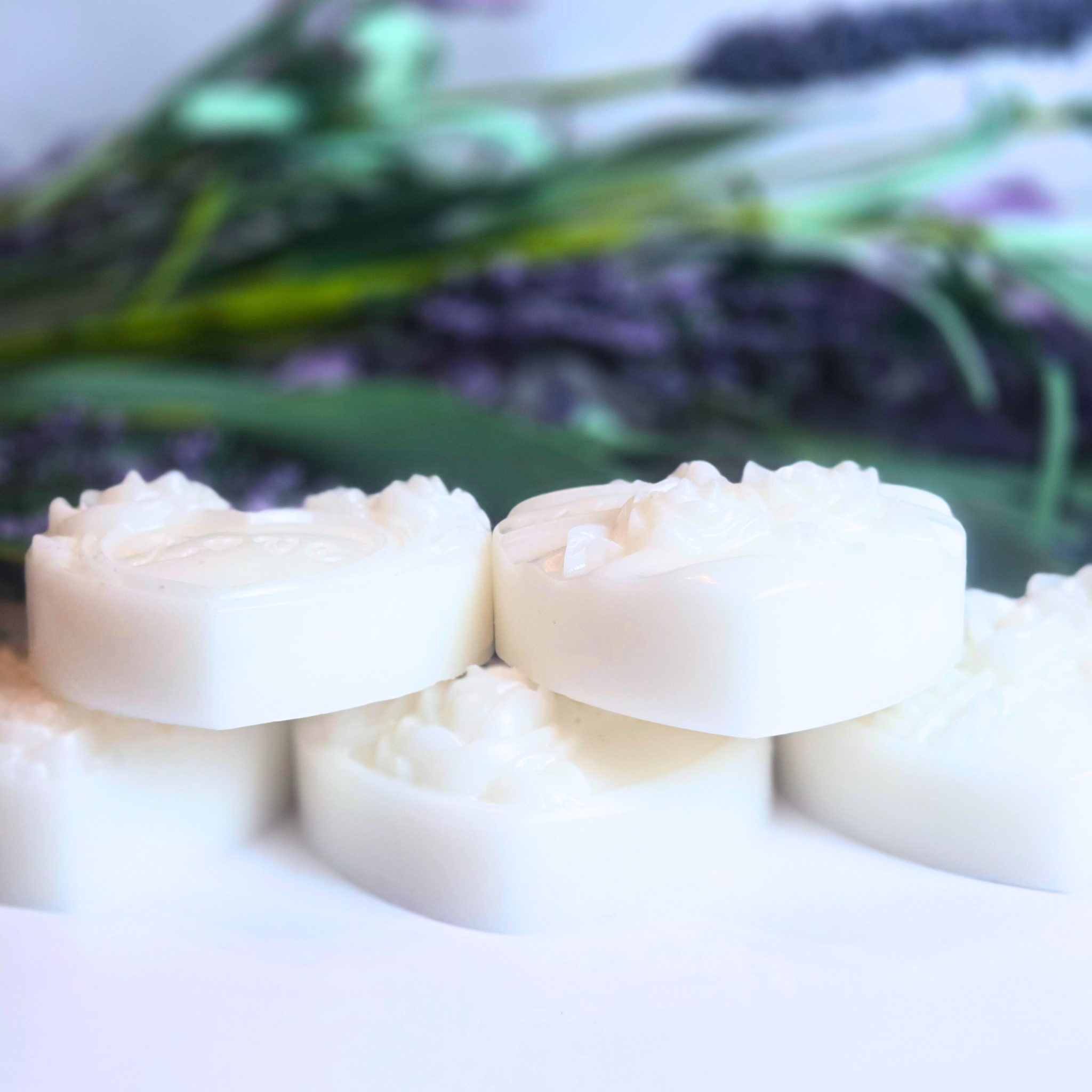 Handcrafted goat milk soap bars in heart shape with floral decoration, side view.