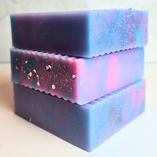 Handcrafted soap with sparkling blue, purple, and pink swirls, side view.